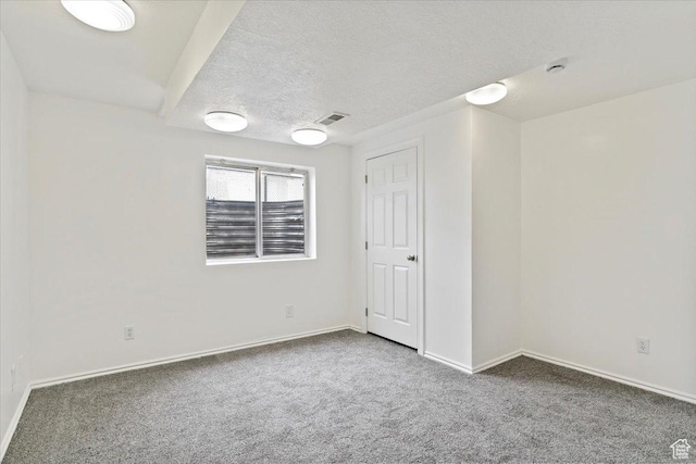 unfurnished room with a textured ceiling, carpet, visible vents, and baseboards