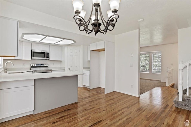 kitchen with white cabinets, light wood-style flooring, stainless steel appliances, and a sink