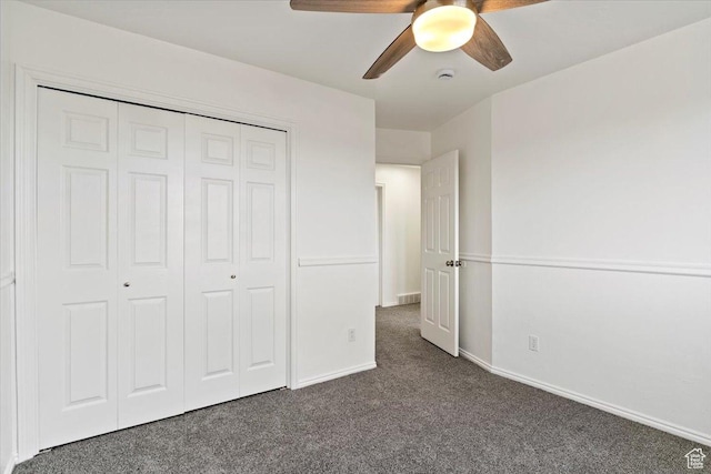 unfurnished bedroom with dark carpet, a closet, a ceiling fan, and baseboards