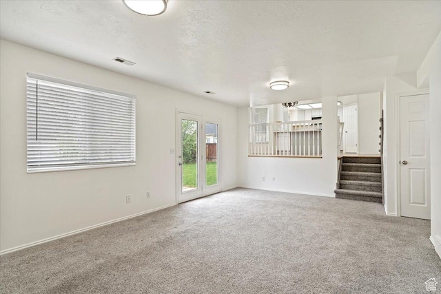 unfurnished living room with stairway, visible vents, carpet flooring, and baseboards