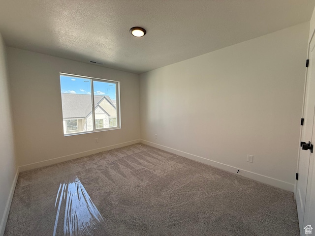 carpeted empty room featuring baseboards and a textured ceiling