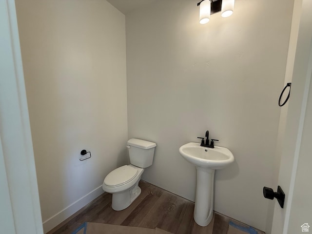 half bathroom with wood finished floors, toilet, and a sink