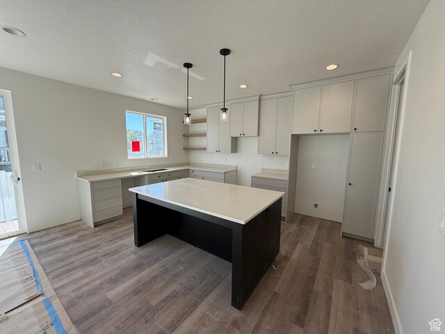 kitchen featuring a center island, wood finished floors, recessed lighting, pendant lighting, and light countertops