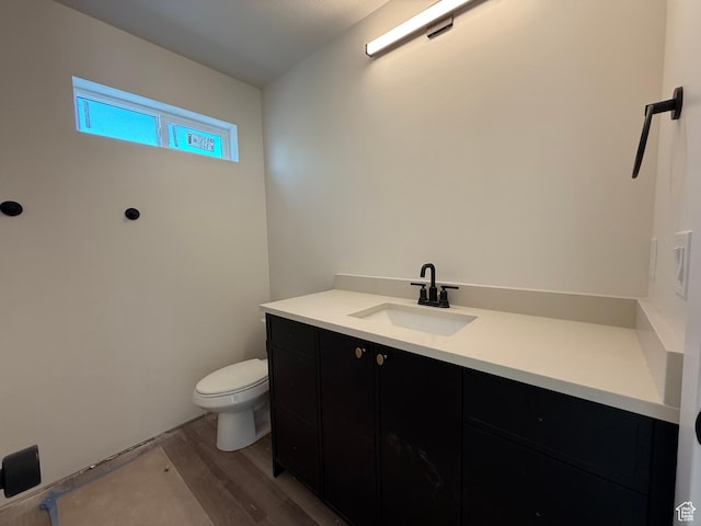 bathroom with wood finished floors, toilet, and vanity