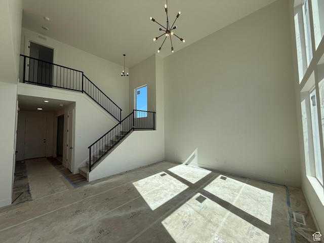 staircase with a chandelier, a high ceiling, plenty of natural light, and baseboards