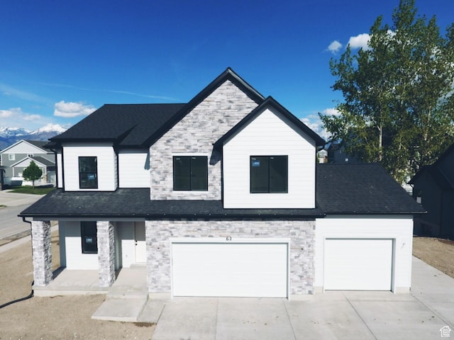 view of front facade featuring stone siding, driveway, an attached garage, and roof with shingles