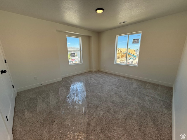 carpeted empty room featuring baseboards and a textured ceiling
