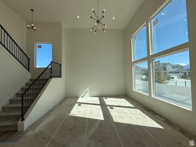 unfurnished dining area with a chandelier, stairs, a high ceiling, and recessed lighting