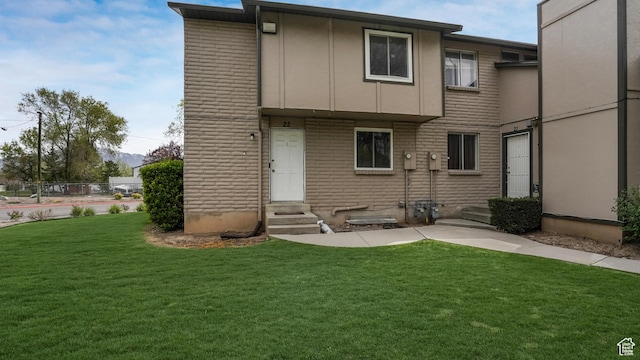 back of property with entry steps and a lawn
