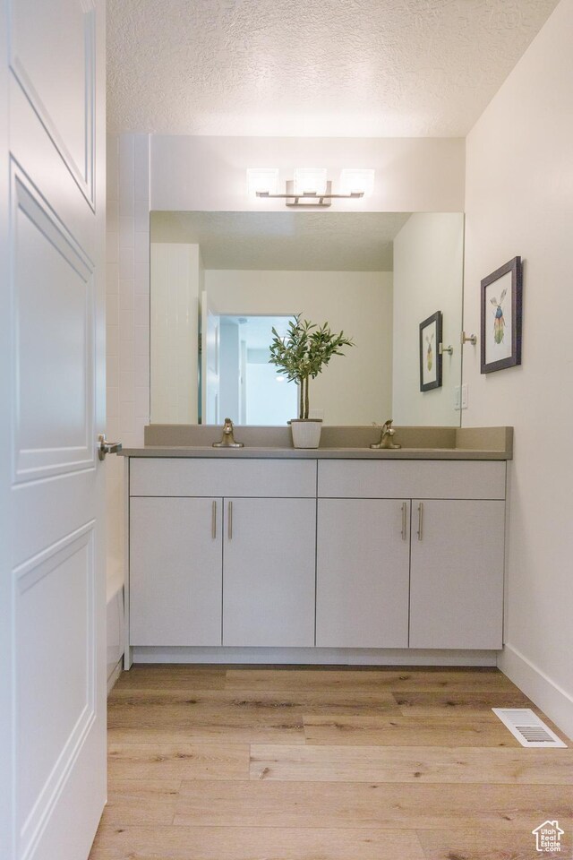 178 W Autumn Ln Unit 136, Saratoga Springs, UT 84045 - bathroom featuring baseboards, double vanity, wood finished floors, and a textured ceiling