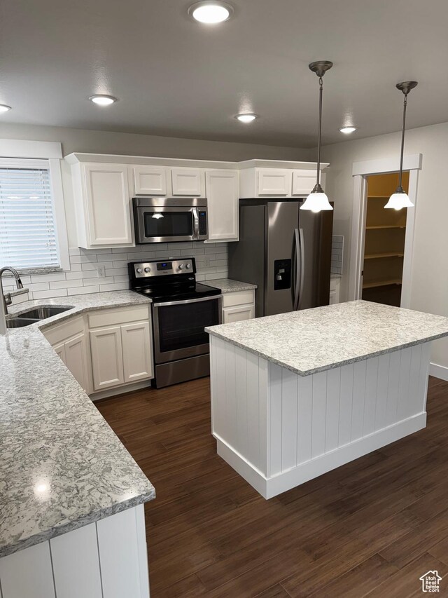 kitchen with white cabinets, a center island, dark wood-style floors, a sink, and appliances with stainless steel finishes