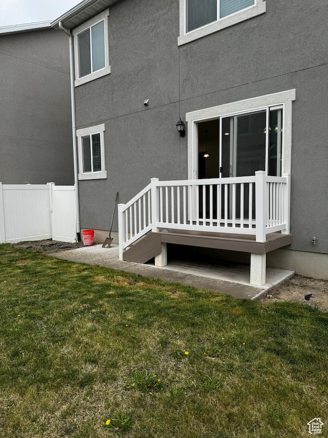 back of property with fence, a lawn, and stucco siding