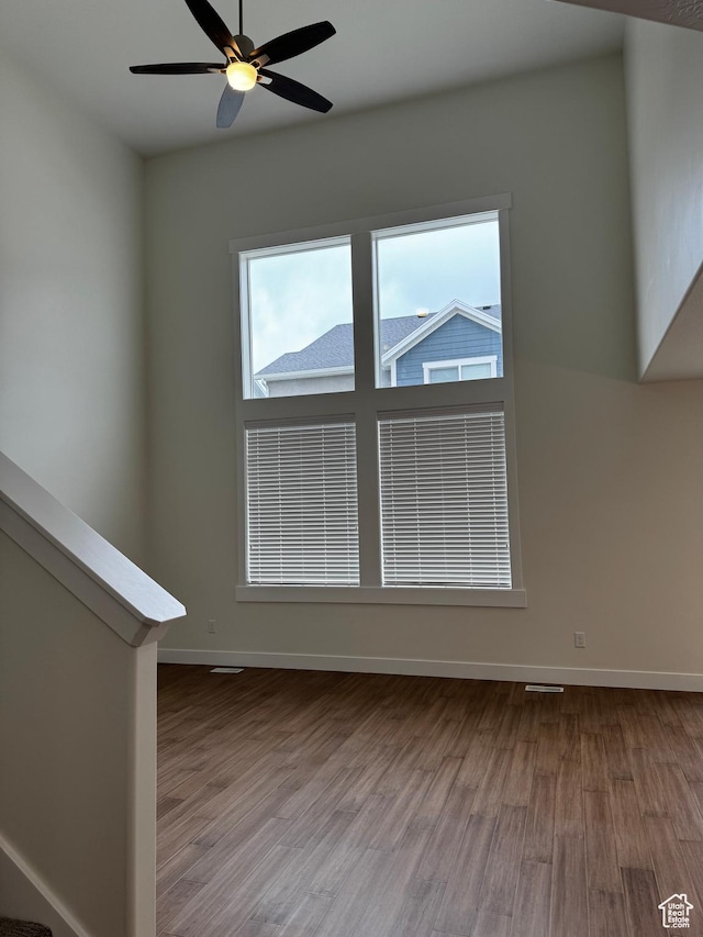 empty room with wood finished floors, baseboards, and ceiling fan