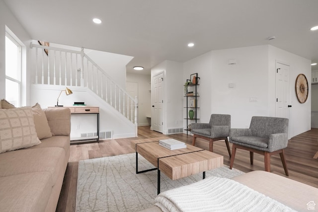 living room featuring recessed lighting, wood finished floors, visible vents, and stairs