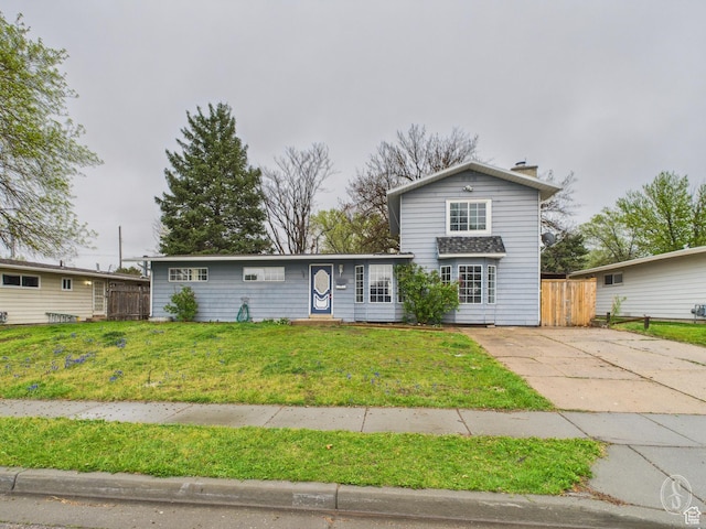 traditional home with a chimney, a front lawn, and fence
