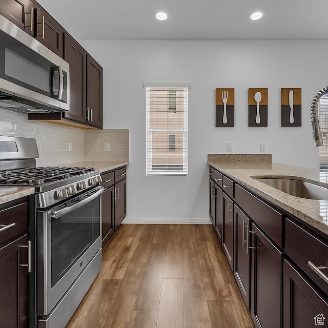14714 S Rising Star Way, Bluffdale, UT 84065 - kitchen with appliances with stainless steel finishes, light stone countertops, dark brown cabinets, dark wood-style flooring, and decorative backsplash