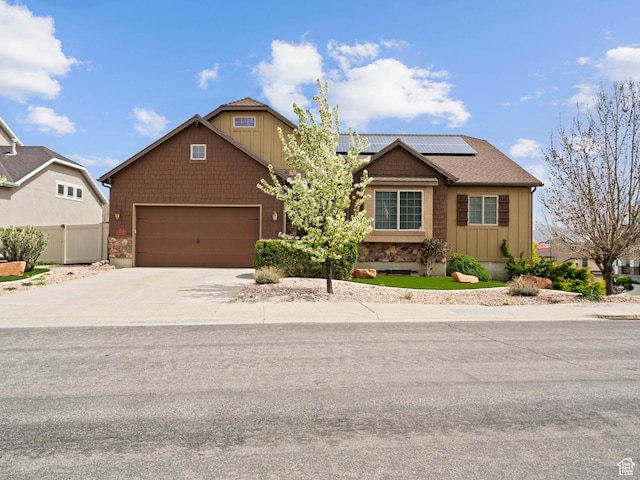 view of front of home featuring roof mounted solar panels, fence, concrete driveway, an attached garage, and board and batten siding