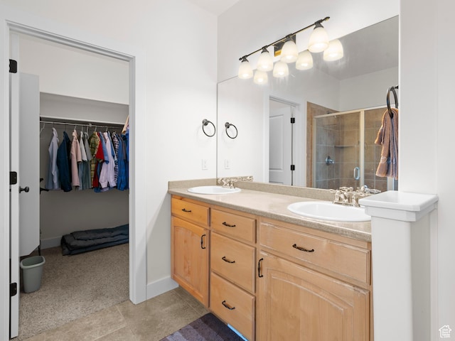 full bath with double vanity, a shower stall, a spacious closet, and a sink