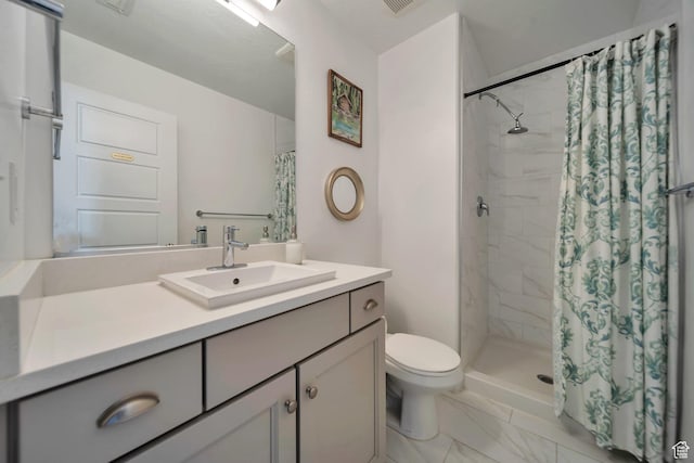 bathroom featuring marble finish floor, a tile shower, toilet, and vanity