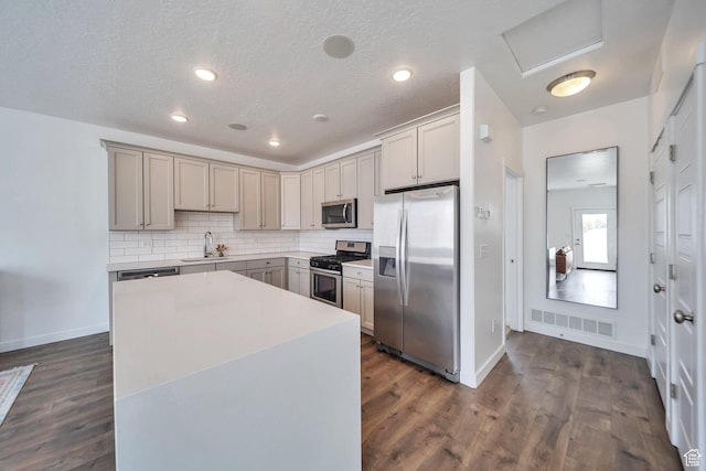 kitchen featuring stainless steel appliances, gray cabinetry, a sink, and dark wood-style flooring