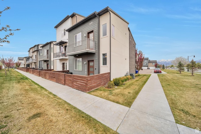 view of home's exterior with a residential view, a yard, and a balcony