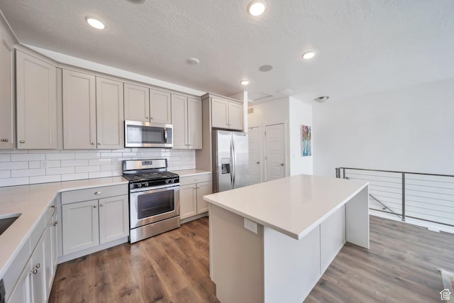 kitchen with stainless steel appliances, a center island, gray cabinetry, and tasteful backsplash
