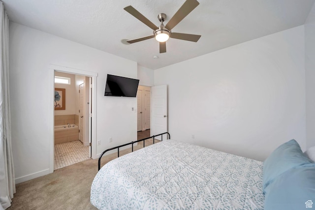 carpeted bedroom with a ceiling fan, baseboards, and ensuite bathroom
