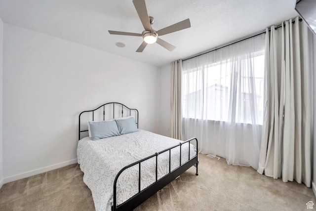 bedroom with light colored carpet, baseboards, and a ceiling fan