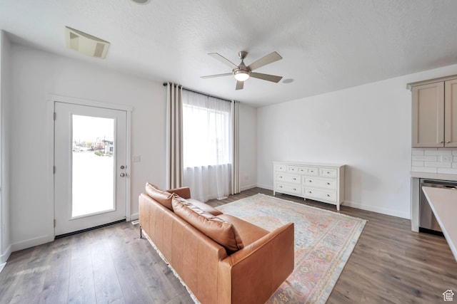 living room with a textured ceiling, baseboards, visible vents, a ceiling fan, and wood finished floors