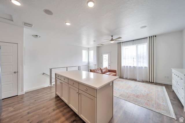kitchen featuring light countertops, wood finished floors, a kitchen island, and ceiling fan