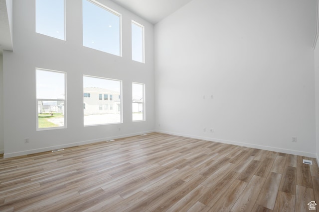 1784 E Bison Dr Unit B234, Eagle Mountain, UT 84005 - unfurnished living room with a high ceiling, light wood-style floors, visible vents, and baseboards