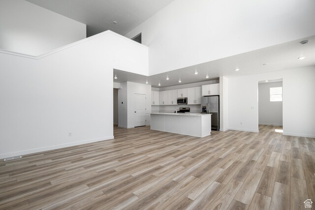 1784 E Bison Dr Unit B234, Eagle Mountain, UT 84005 - unfurnished living room featuring recessed lighting, light wood-style flooring, a towering ceiling, and baseboards
