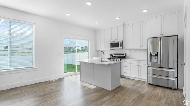 794 Brook Ave E, Tooele, UT 84074 - kitchen with white cabinets, backsplash, a sink, light wood-style floors, and appliances with stainless steel finishes