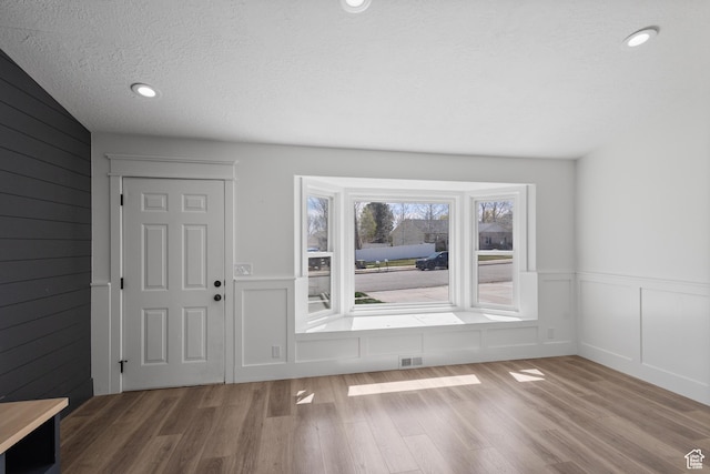 entrance foyer with recessed lighting, a textured ceiling, wood finished floors, and a decorative wall