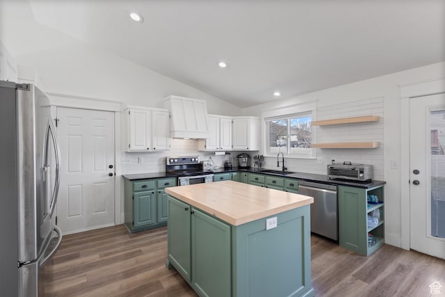 kitchen featuring stainless steel appliances, a sink, green cabinetry, lofted ceiling, and wood counters