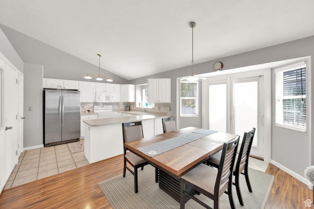 dining space with vaulted ceiling, baseboards, and light wood-style floors