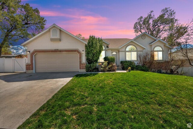 single story home featuring an attached garage, fence, concrete driveway, and a lawn