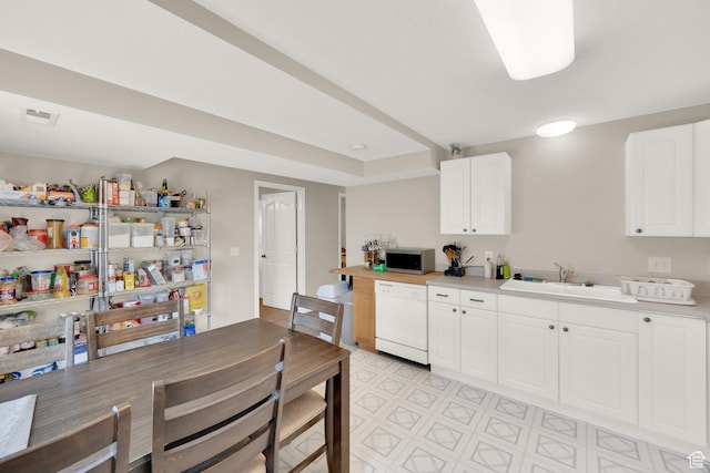 kitchen with white dishwasher, light countertops, stainless steel microwave, and a sink