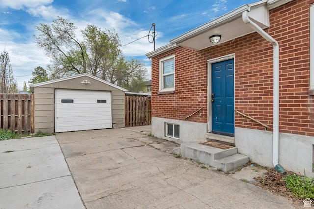 entrance to property featuring fence, brick siding, and a detached garage