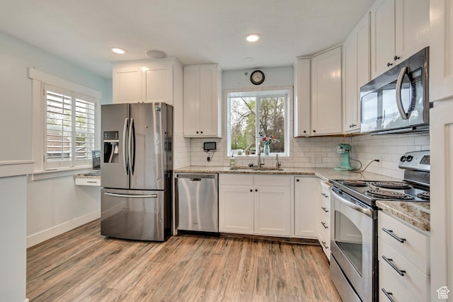 kitchen with white cabinetry, a sink, light wood-style floors, and appliances with stainless steel finishes