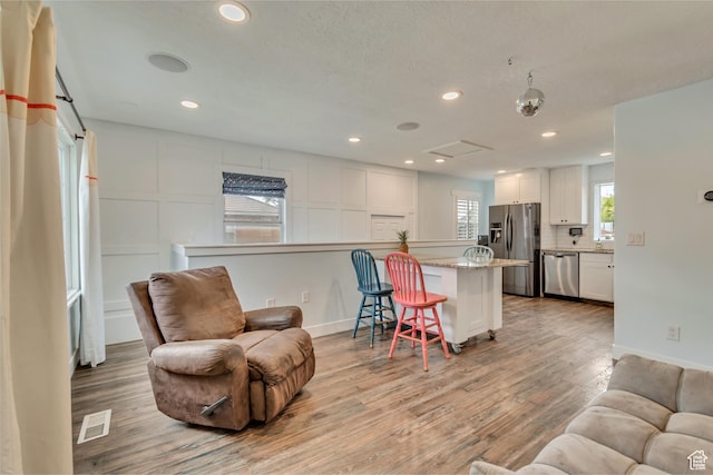 living room featuring recessed lighting, visible vents, light wood finished floors, and baseboards