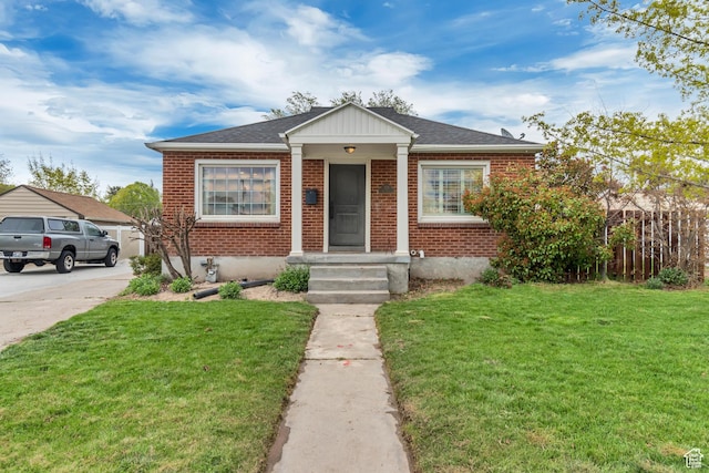 bungalow featuring a front lawn, brick siding, and a shingled roof