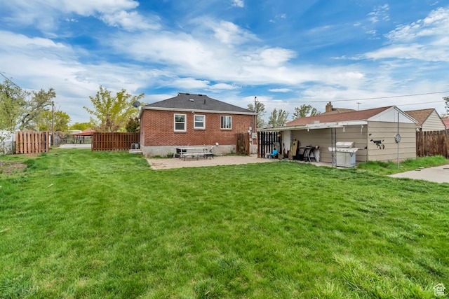 back of property with fence, brick siding, a yard, and a patio