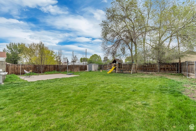 view of yard featuring a playground, a fenced backyard, an outdoor structure, a patio, and a storage unit
