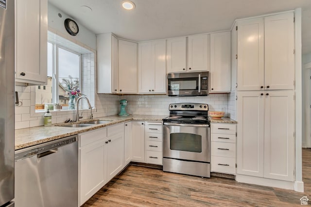 kitchen featuring appliances with stainless steel finishes, tasteful backsplash, a sink, and white cabinetry