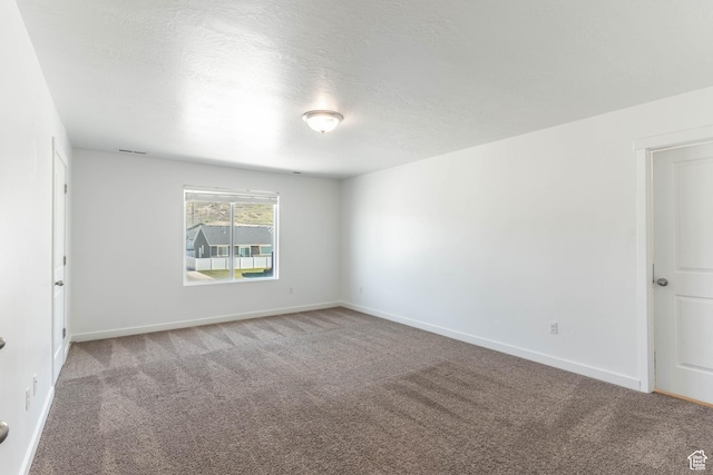 carpeted empty room featuring baseboards and a textured ceiling