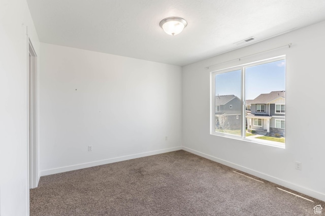 spare room with carpet floors, visible vents, and baseboards