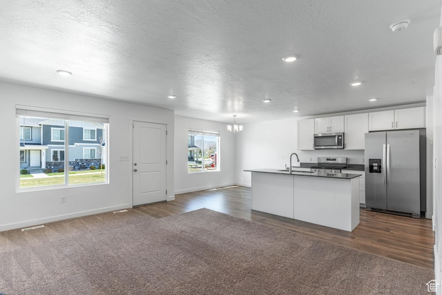 kitchen featuring white cabinets, an inviting chandelier, dark countertops, appliances with stainless steel finishes, and open floor plan