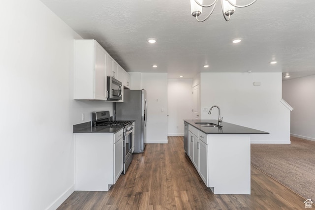 kitchen featuring white cabinets, dark countertops, a sink, baseboards, and appliances with stainless steel finishes