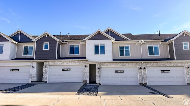 view of property with stone siding, driveway, board and batten siding, and a garage